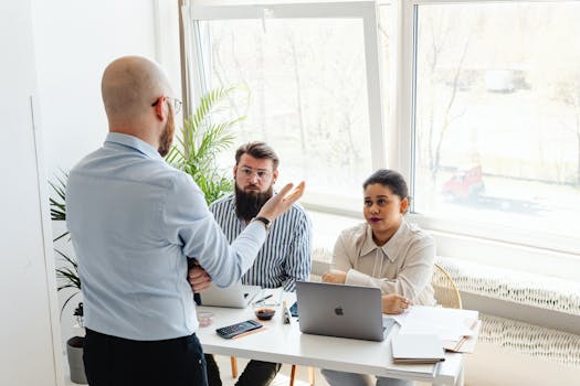 Diverse group of colleagues engaged in a teamwork discussion around a desk in a modern office.