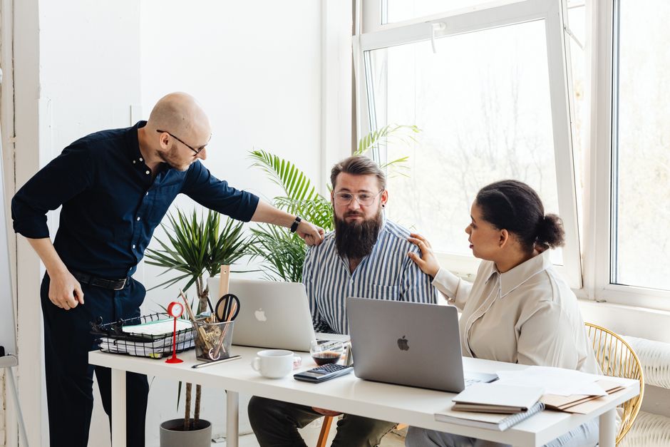 How Password Managers Generate and Store Unique Passwords Securely Three colleagues collaborating at a desk in a bright office space.