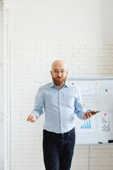 A bald man with eyeglasses presenting data on charts in a modern office setting.