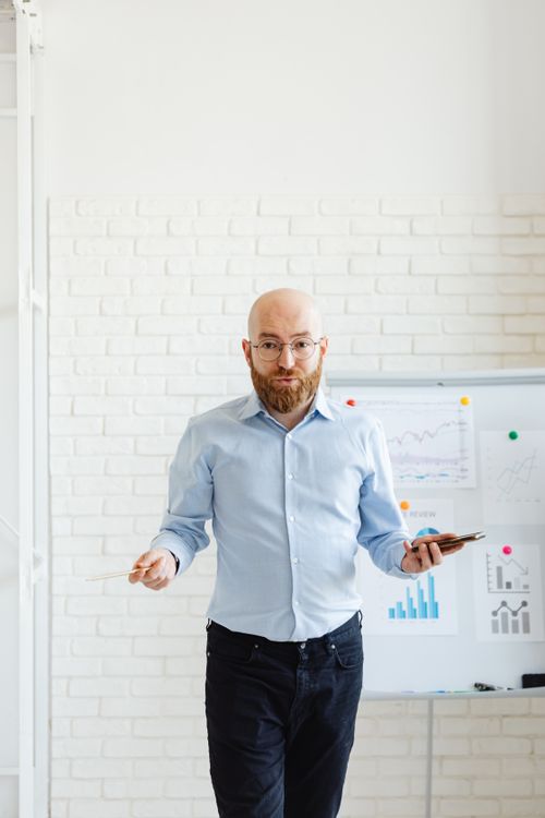 Free A bald man with eyeglasses presenting data on charts in a modern office setting. Stock Photo