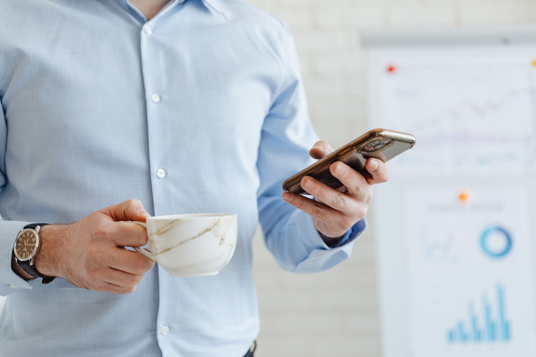 A person reading email on a phone at a kitchen table, where most coaching newsletters are actually opened