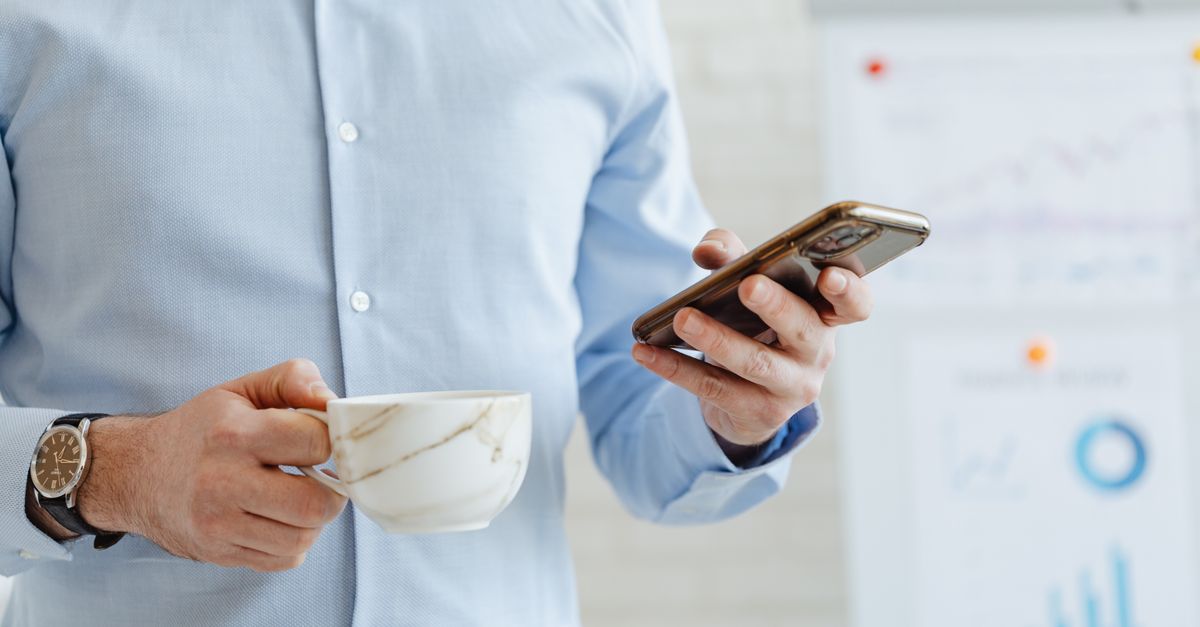 person reading newsletter on smartphone morning coffee email inbox
