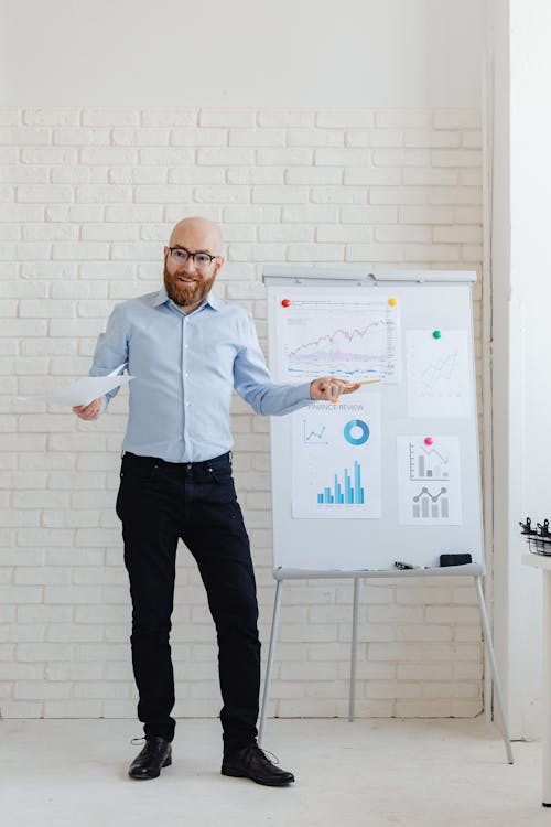 A Man Standing Beside a White Board with Posted Graphs and Charts