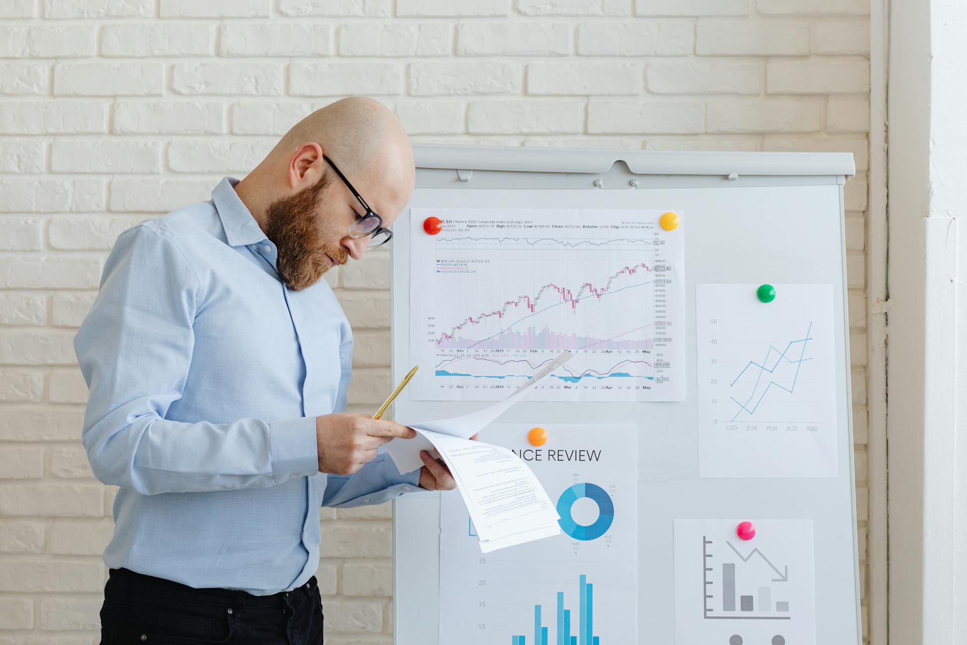 Business person in an office reviewing financial documents on a whiteboard.