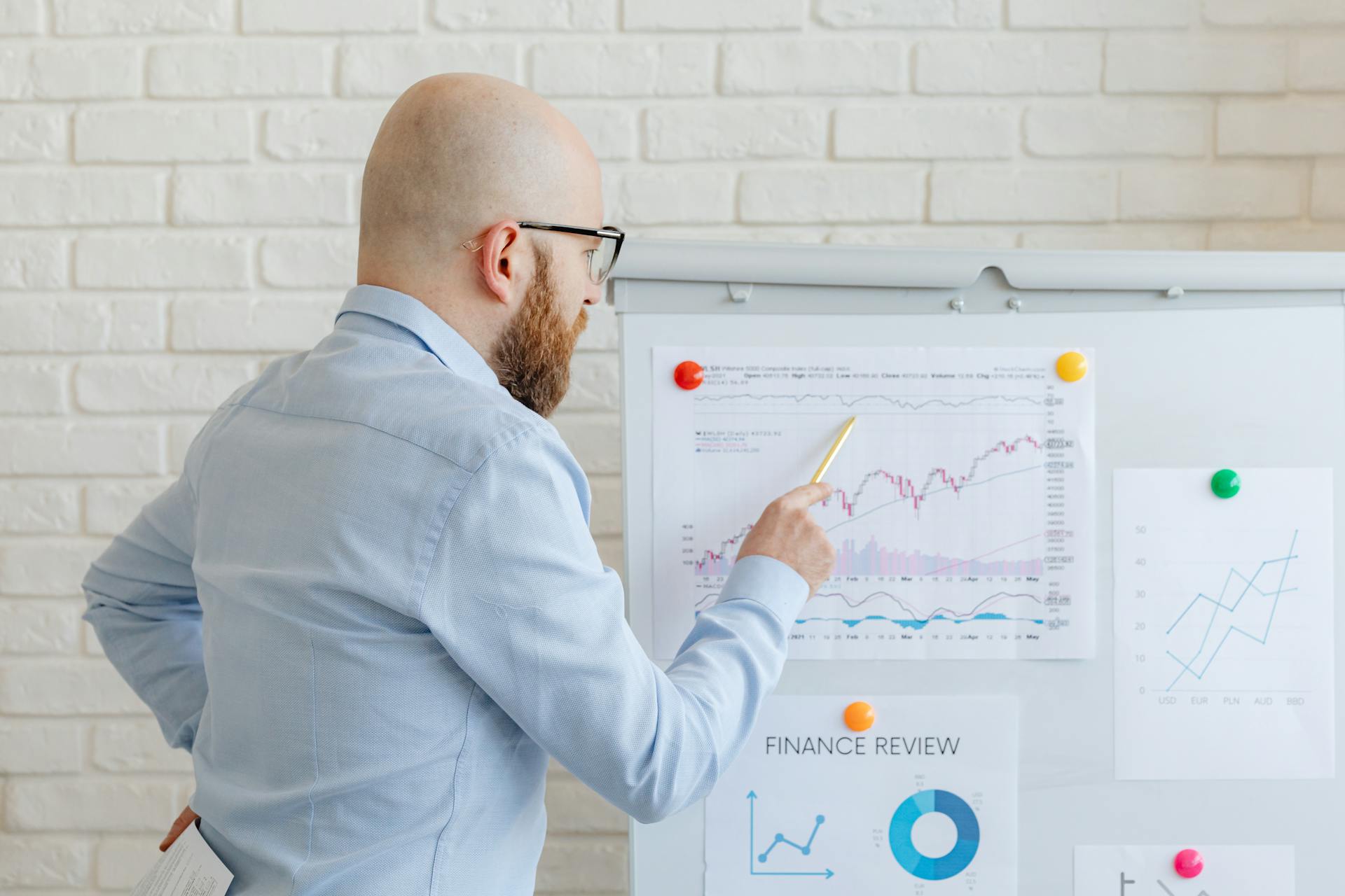 Bald Man Standing by Whiteboard with Charts