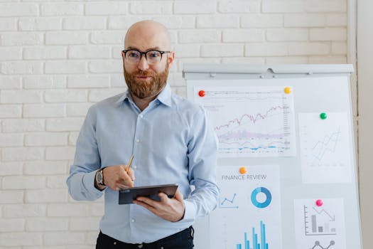 Businessman presenting financial analysis with charts on a flipchart in a modern office setting.