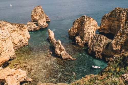 Free Majestic rock formations towering over turquoise sea water on a sunny day. Stock Photo