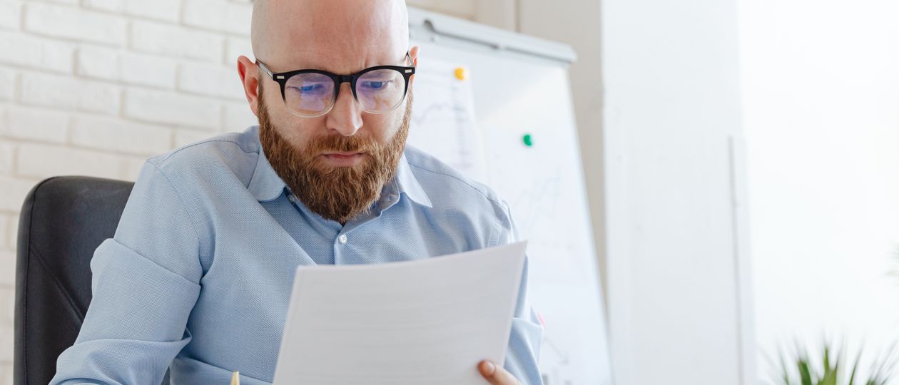 Medewerker met bril neemt documenten door op kantoor