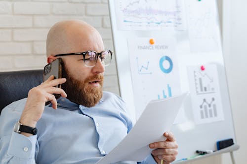 Free A Man Talking on the Phone While Looking at Documents Stock Photo