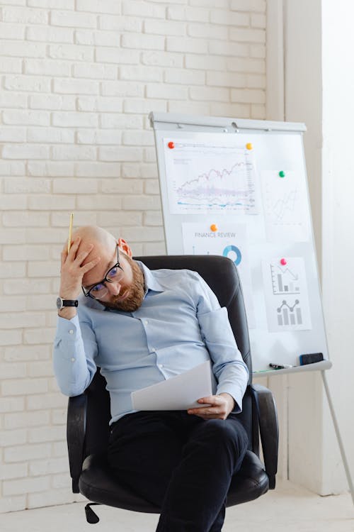 Free Man in Blue Long Sleeve Shirt Sitting on Black Office Chair Stock Photo