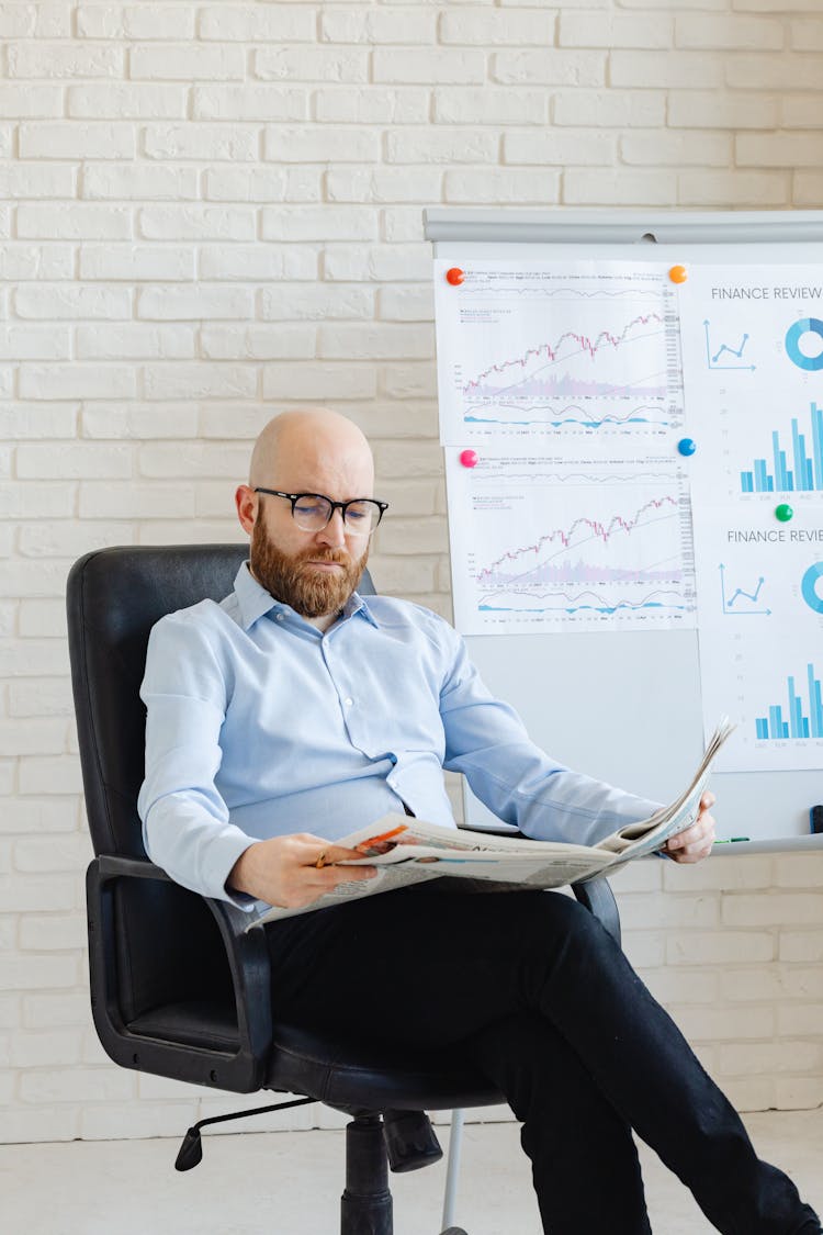 A Man In Corporate Attire Reading A Newspaper