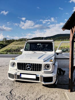 A luxurious Mercedes-Benz G-Class SUV parked in a picturesque outdoor setting, showcasing an elegant design and scenic mountain backdrop.