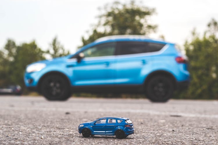 Blue Toy Car Near A Blue Car 