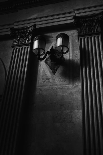 Stunning black and white image of an ornate interior with classic architectural details and vintage lighting.