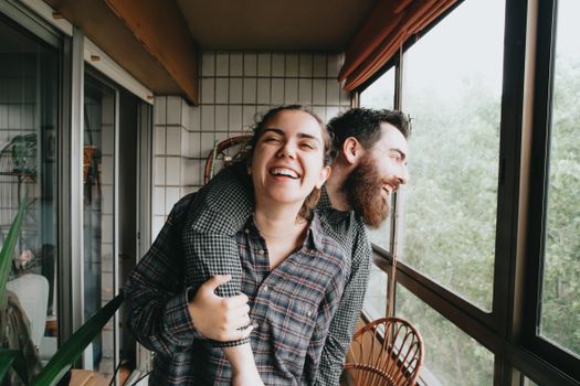 Smiling couple enjoying togetherness on a sunny balcony, exuding happiness.