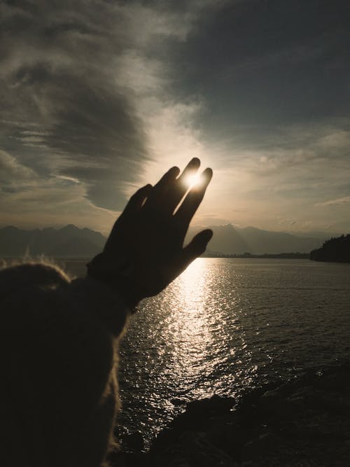 Free A Person Hand Covering the Sun Stock Photo