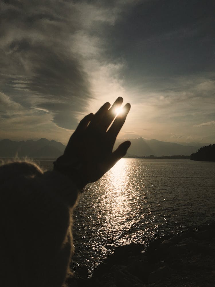 A Person Hand Covering The Sun