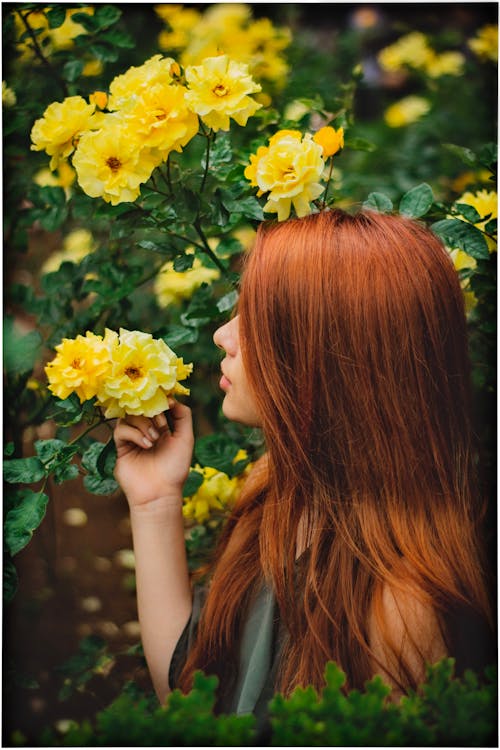 Redhead Woman Smelling Yellow Roses