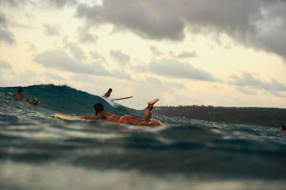 Surfers paddling in the ocean waves, capturing the essence of an adventurous surfing day under an evening sky.