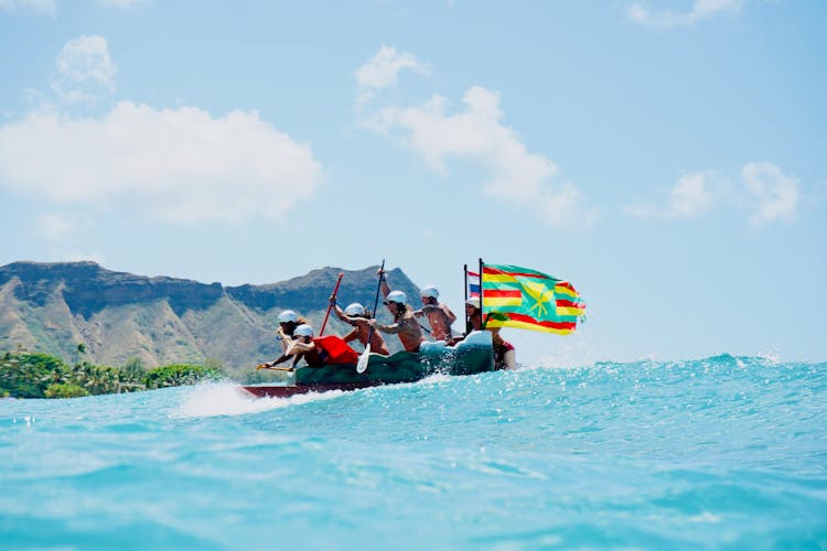 A Group Of People Paddling A Canoe With Flags