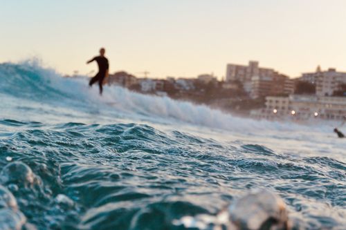 Free A surfer rides waves at Bondi Beach, Sydney, during a stunning day. Stock Photo