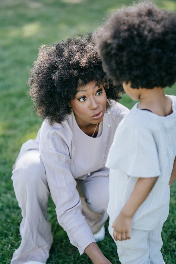 A Woman Kneeling Down Talking To A Child