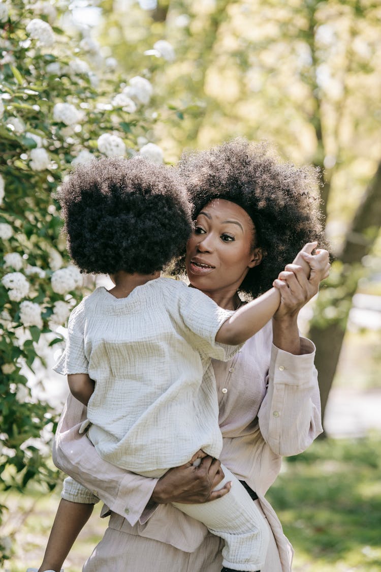 A Woman Carrying A Child While Holding Her Arm