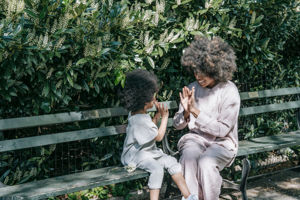 Mother and child playing a clapping game on a bench