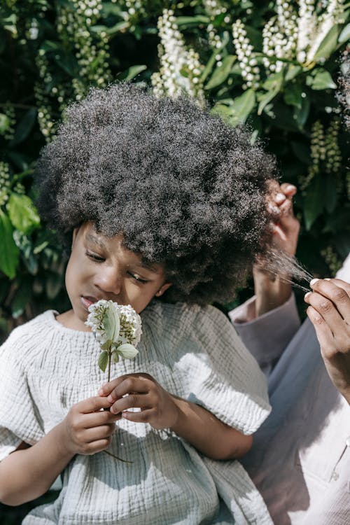 A Person Holding the Hair of a Girl Holding White Flowers