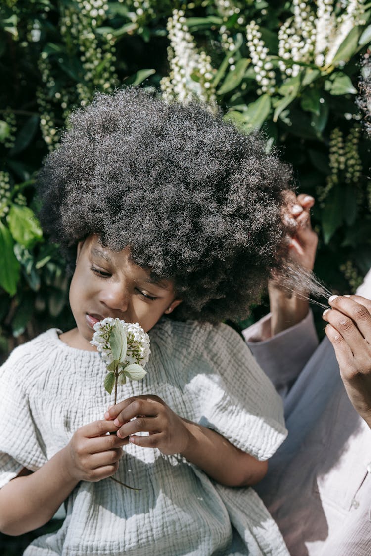 A Person Holding The Hair Of A Girl Holding White Flowers