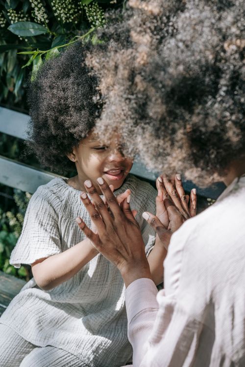 Free Mother and daughter enjoying quality time together in a sunlit garden setting, sharing a playful moment. Stock Photo