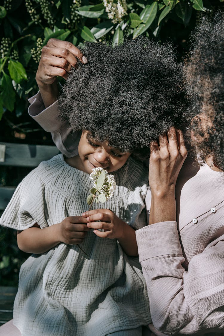 A Little Girl Smelling A Flower