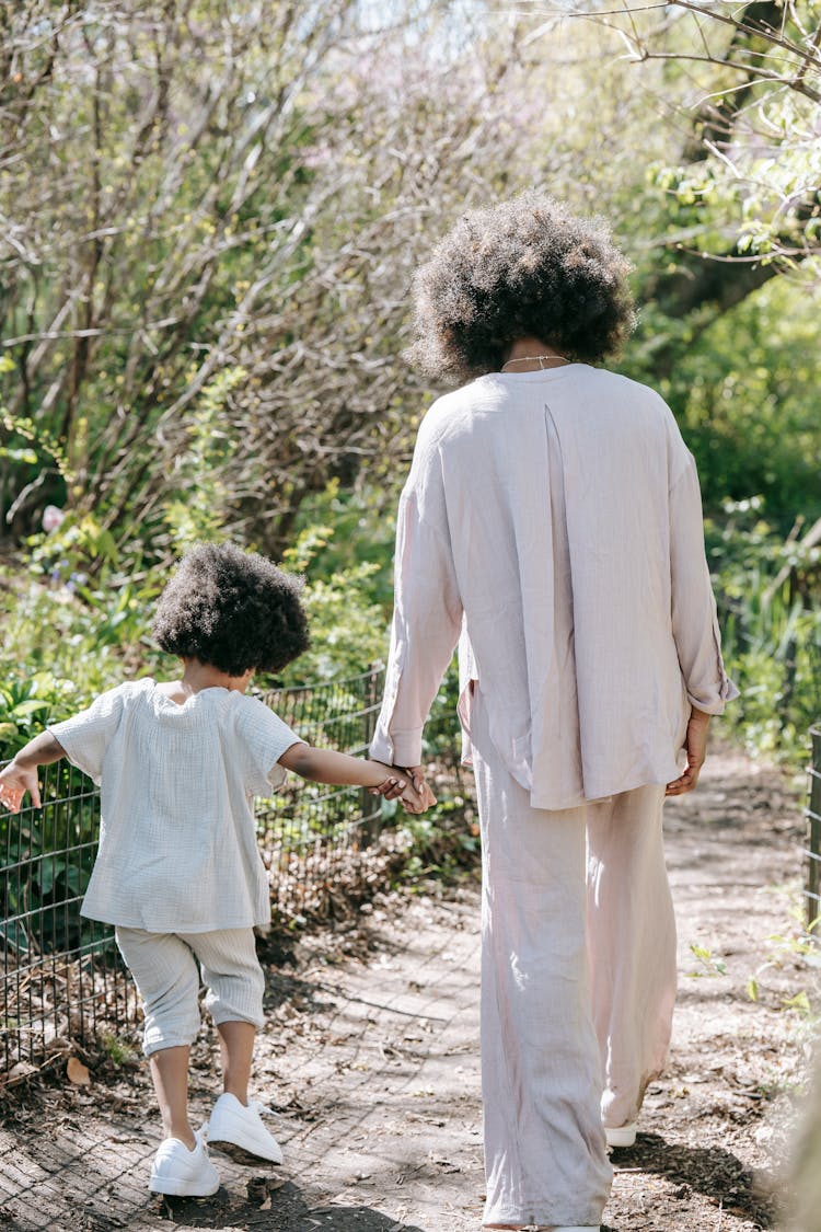 A Mother And Child Walking Together While Holding Hands