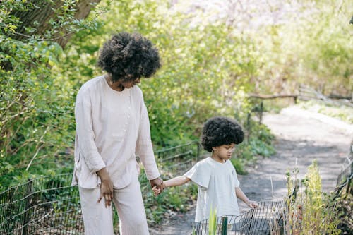 A Woman Holding Hands with her Daughter at a Park