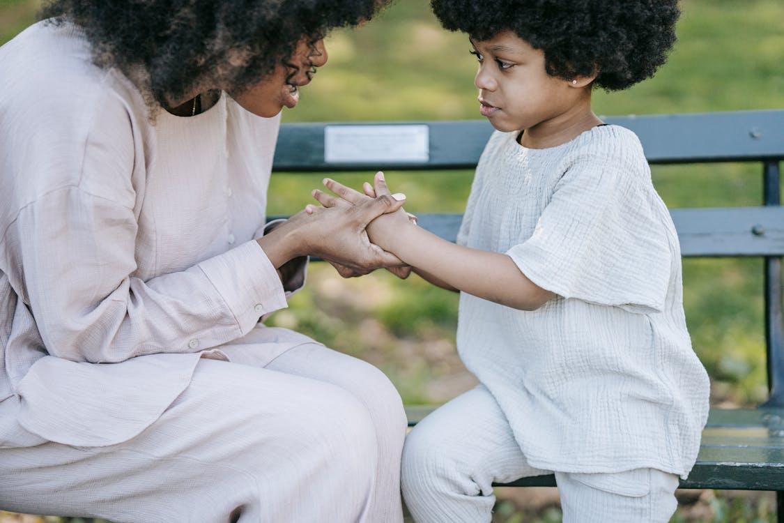 Woman Talking to the Girl while Holding her Hands 