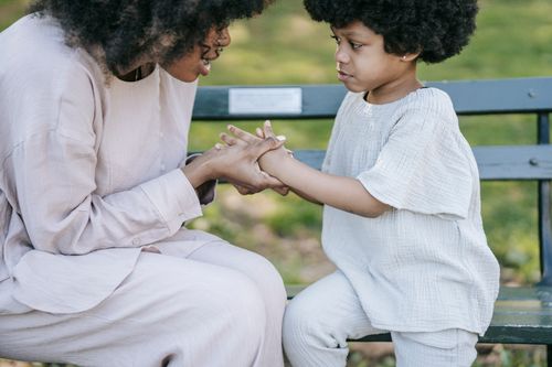 Free A mother and child sharing a heartfelt moment of connection and affection on a park bench outdoors. Stock Photo