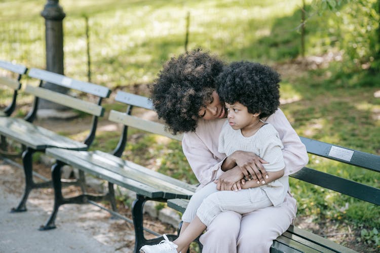 Curly Haired Girl Sitting On The Woman's Lap 