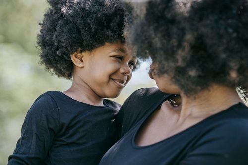 Free Heartwarming close-up of mom and daughter bonding with smiles on a sunny day. Stock Photo