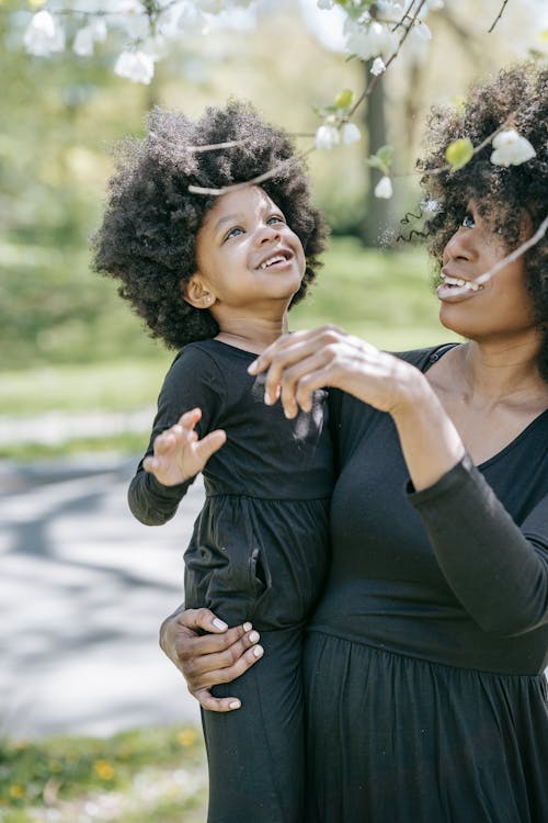Free A Woman Carrying her Daughter at a Park Stock Photo
