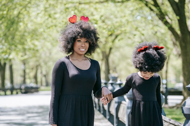 A Mother And Daughter In Black Clothing And Red Heart Headbands