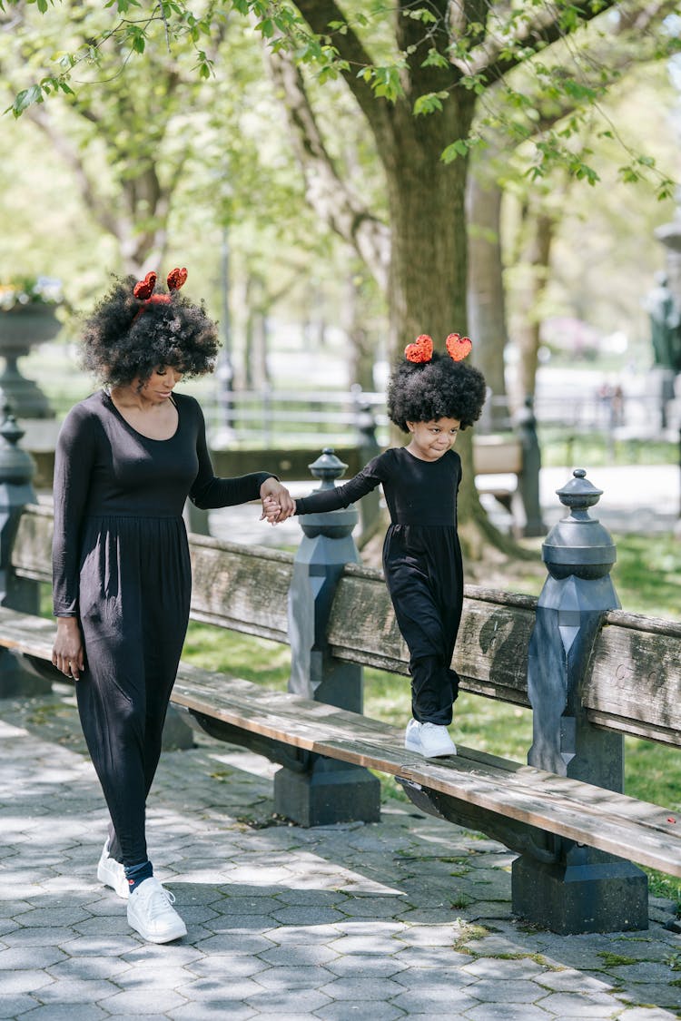 A Mother And A Girl In Matching Outfits With Heart Headbands Walking 