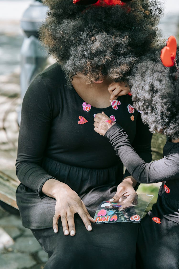 A Child Placing Stickers On Her Mom