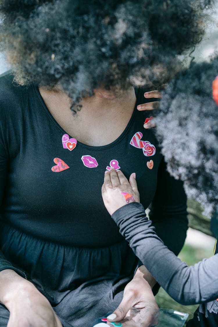 A Child Placing Stickers On Her Mom