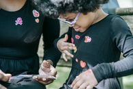 A Girl Sticking a Heart Sticker on her Shirt
