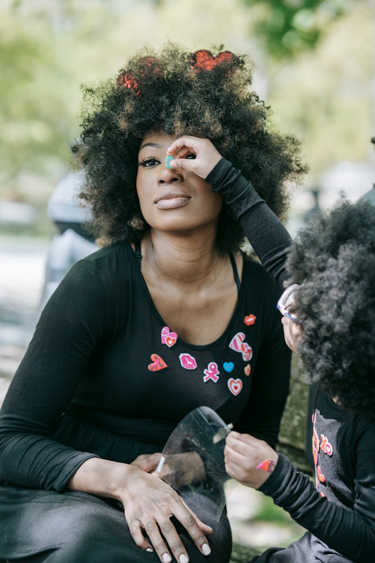 A Child Putting A Sticker On A Woman's Nose