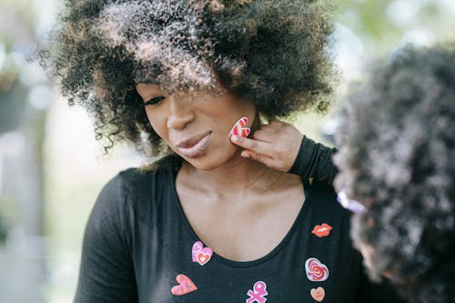 A Child Sticking a Heart Sticker on a Woman's Face