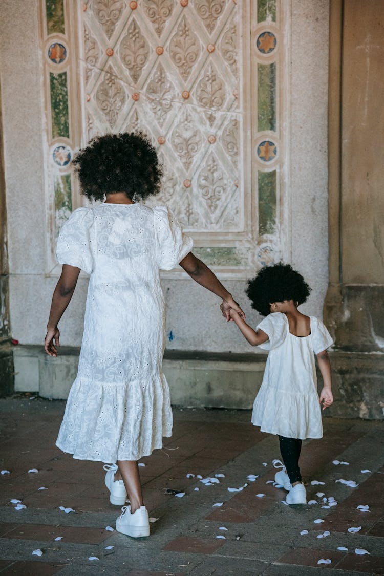 A Woman And A Girl Walking On A Floor With Flower Petals