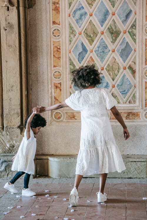 A Woman and a  Girl Walking on a Floor with Flower Petals