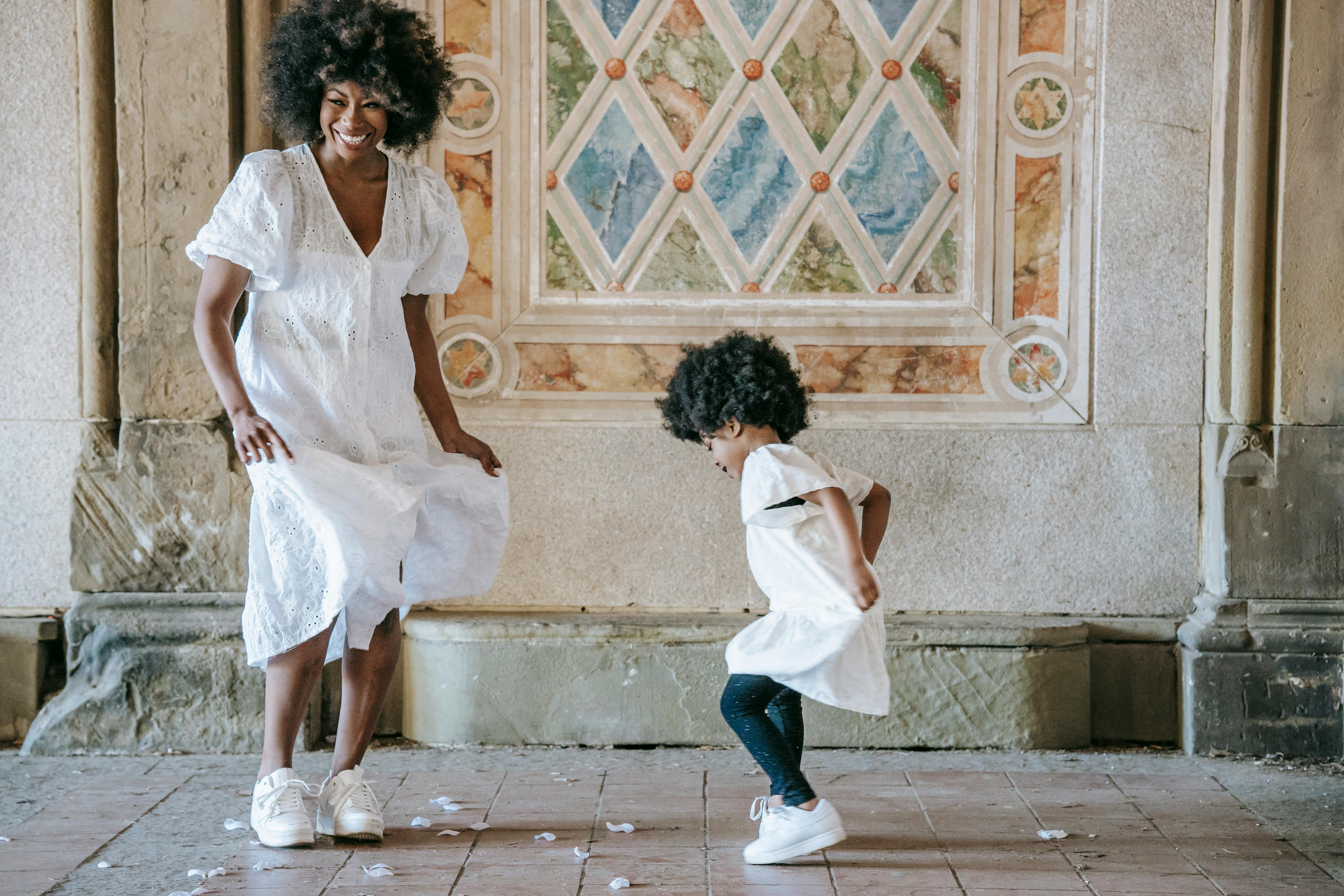 a woman and a girl in white dress dancing