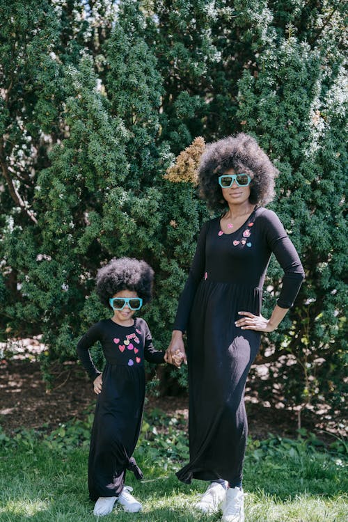 A Woman and a Girl in Matching Outfits Posing on Green Grass